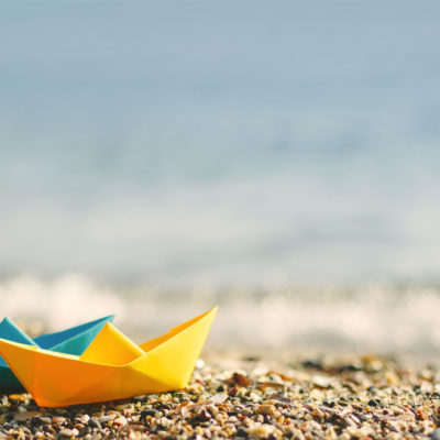 two paper sail boats on a beach