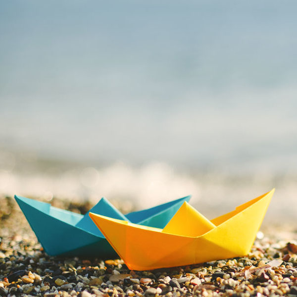 two paper sail boats on a beach