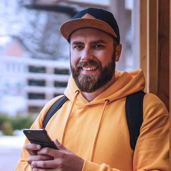 Man in a Hat with a Yellow Hoodie Holding a Phone