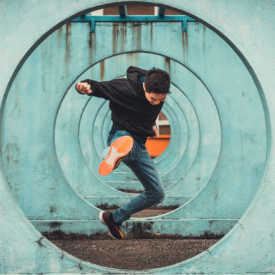 Guy jumping through colored tunnel.