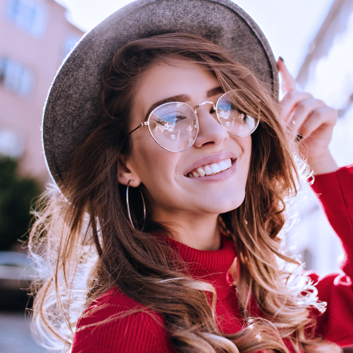 Girl wearing red sweater and glasses smiling at the camera.