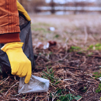 Girl picking up trash with a yellow glove.