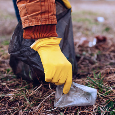 Girl picking up trash with a yellow glove.
