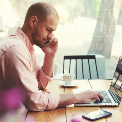 Man Using Laptop and Phone