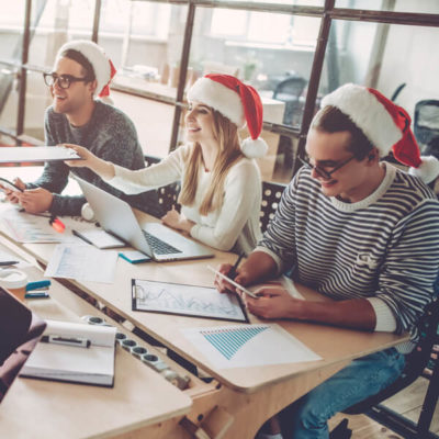 Coworkers create holiday marketing ideas at a conference table.
