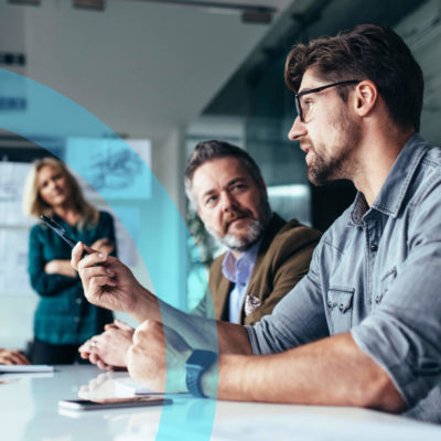 A man talks with clients at a work table.