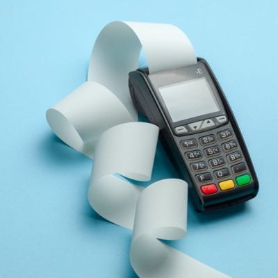 Terminal cash register machine POS for payments and long roll cash tape on blue background.