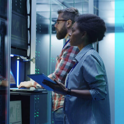 A man and a woman work on a computer server together.