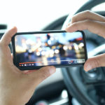 Close up of men's hands holding mobile phone while play video from network in parking lot