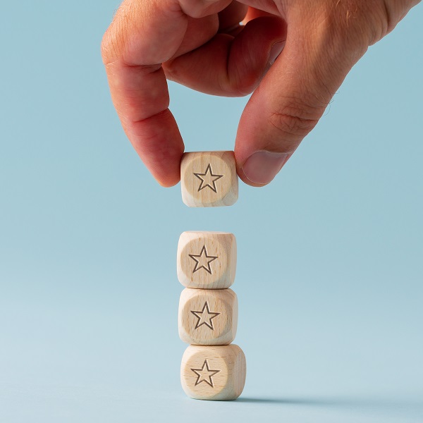 Male hand stacking five wooden dices with star shape on them