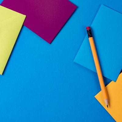 different colored envelopes with a pencil behind a blue background