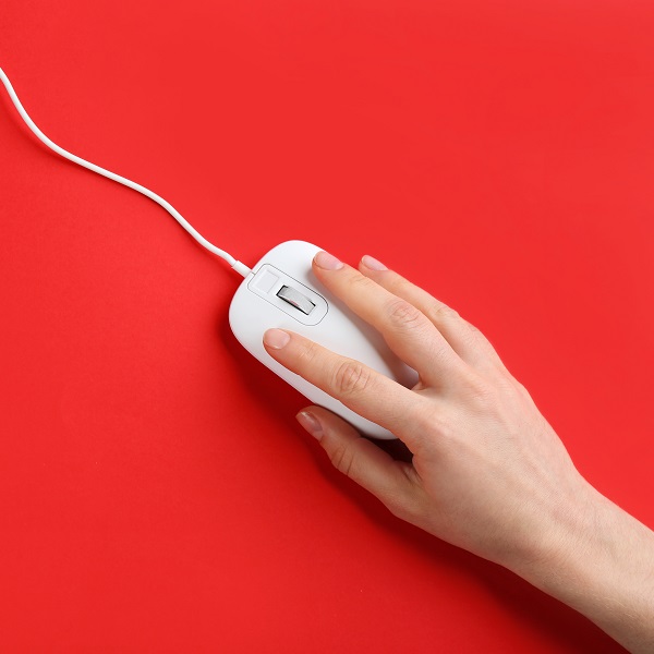 Woman using modern wired optical mouse on red background, top view. Space for text