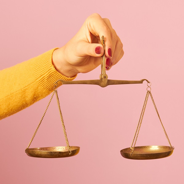 woman hand holding a balance on pink background