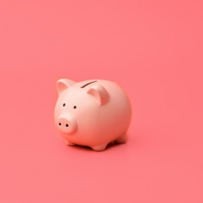 Pink piggy Bank stands in the center on a pink background. Horizontal photography