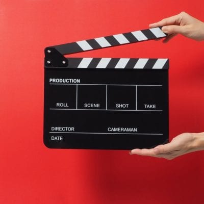 Hand is holding black Clapper board or movie slate. it use in video production ,film, cinema industry on red background.