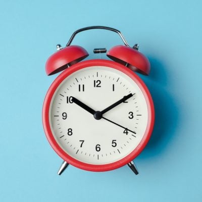 Red vintage alarm clock on light blue color background