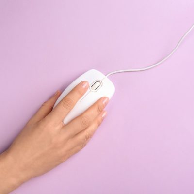 Woman using modern wired optical mouse on lilac background, top view. Space for text