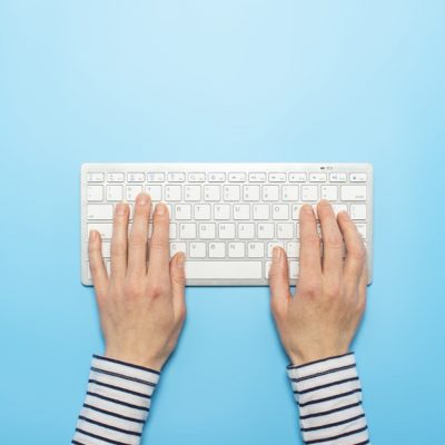 Female hands on a keyboard on a blue background. Concept of offi