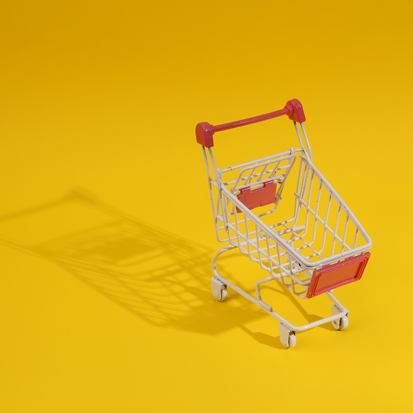 White shopping trolley on yellow background with long shadow