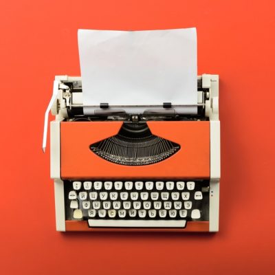 Red vintage typewriter with white blank paper sheet