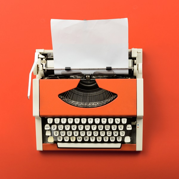 Red vintage typewriter with white blank paper sheet