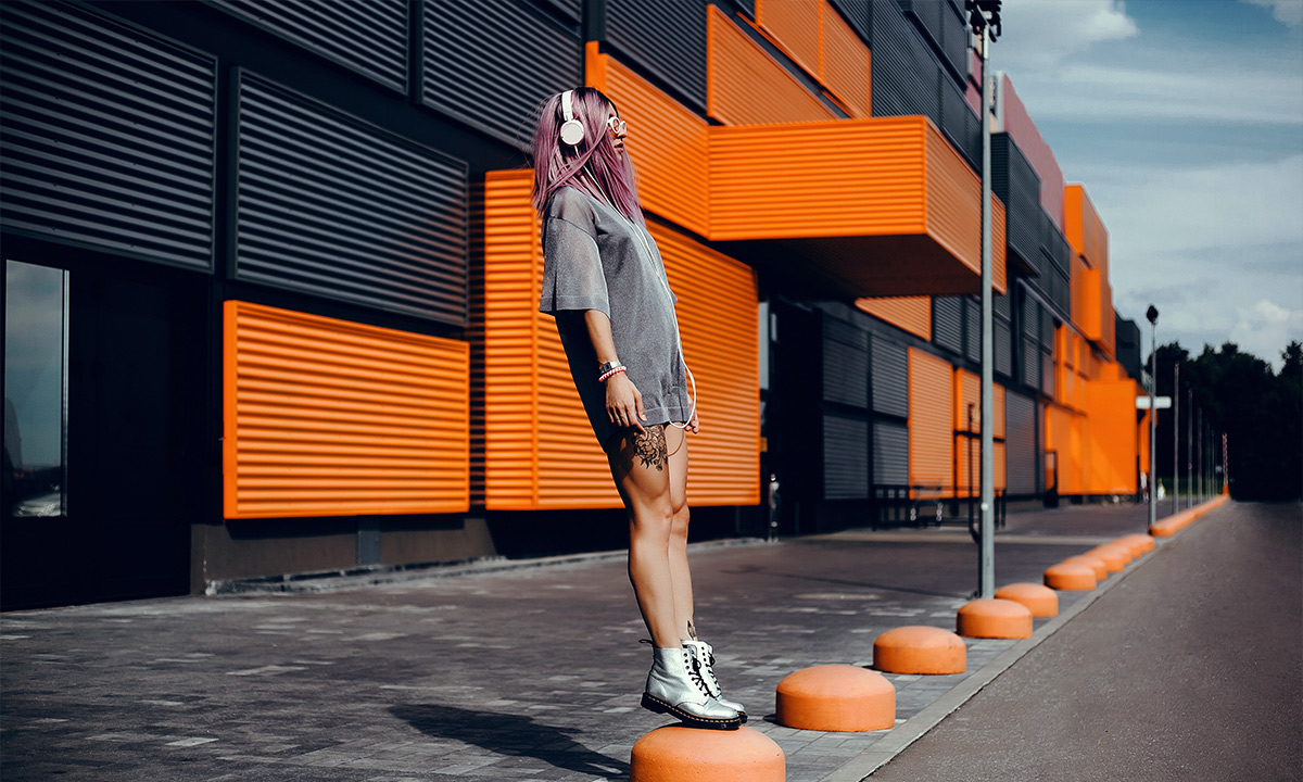 Girl with pink hair listening to headphones.