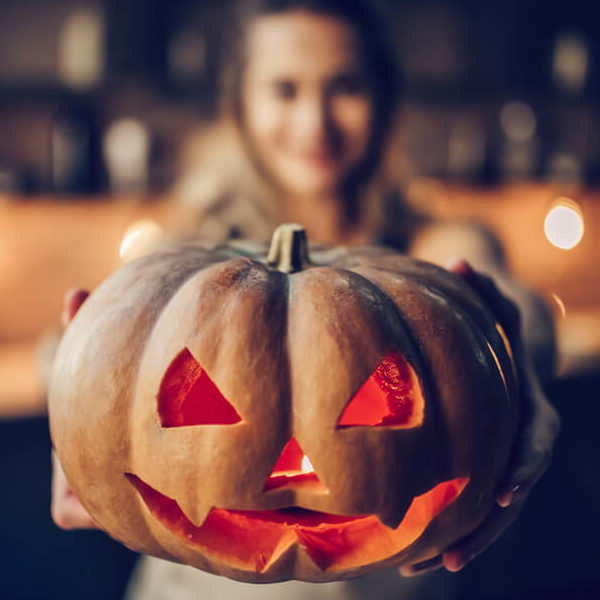 shutterstock_722412394 (1) Woman holding a jack o' lantern.