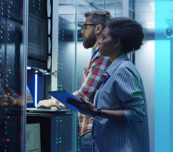 A man and a woman work on a computer server together.