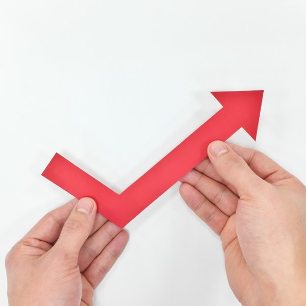 Hand holding red arrow upward. Economy and business recovery and rebound. Hand holding red arrow upward. Economy and business recovery and rebound.