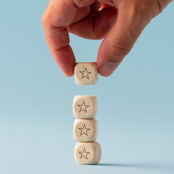 Male hand stacking five wooden dices with star shape on them Male hand stacking five wooden dices with star shape on them